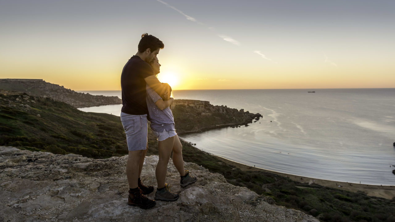 a couple in Malta watching the sunset and embracing